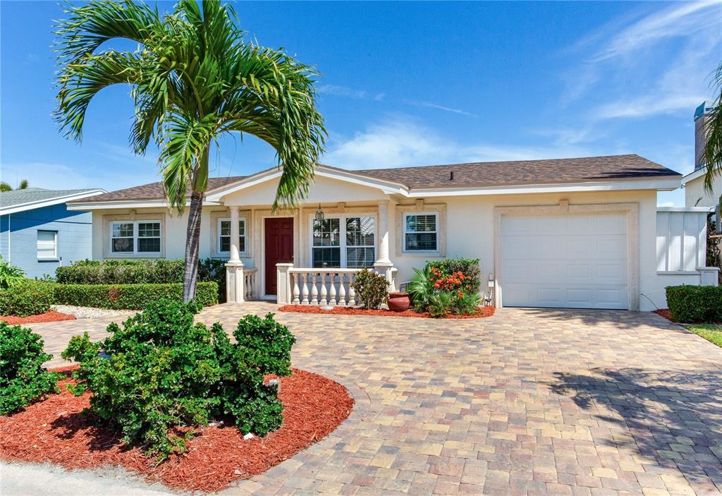 A single-story house with a paved driveway, a palm tree, and a white garage door — 324 173RD AVENUE E, NORTH REDINGTON BEACH, FL