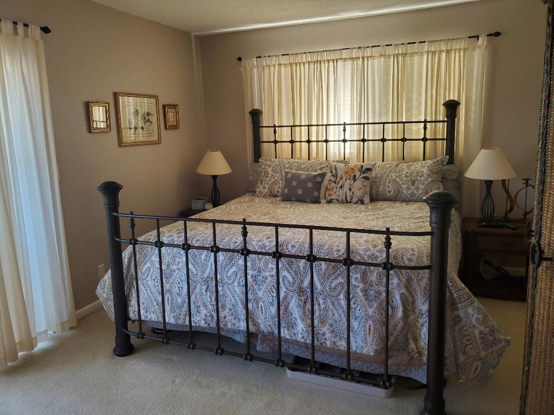 A bedroom features a dark metal bed frame, paisley bedding, and beige curtains — 73 Andover C, West Palm Beach FL 33417, WEST PALM BEACH, FL