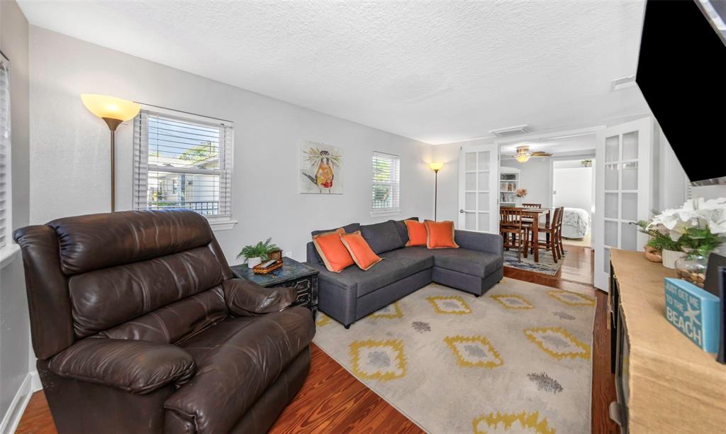 A living room features a brown leather recliner, a gray sectional sofa, and wood flooring — 414 TAMPA ROAD, PALM HARBOR, FL