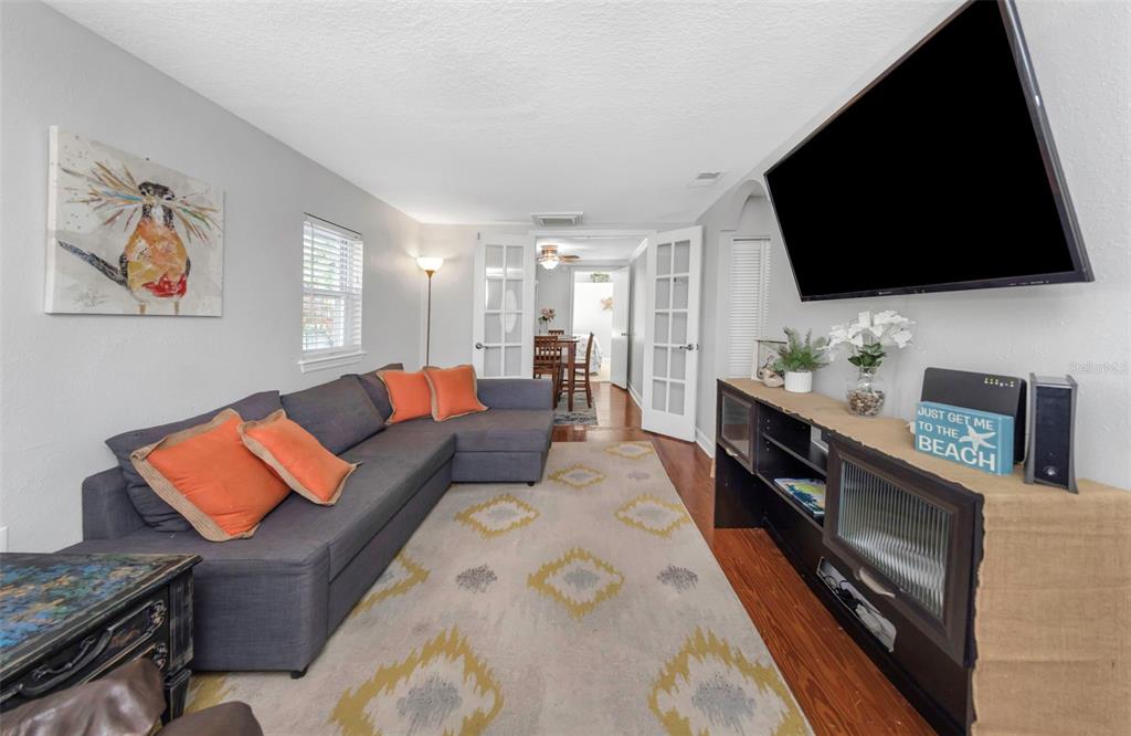 A living room features a gray sectional sofa, a television, and a patterned area rug — 414 TAMPA ROAD, PALM HARBOR, FL