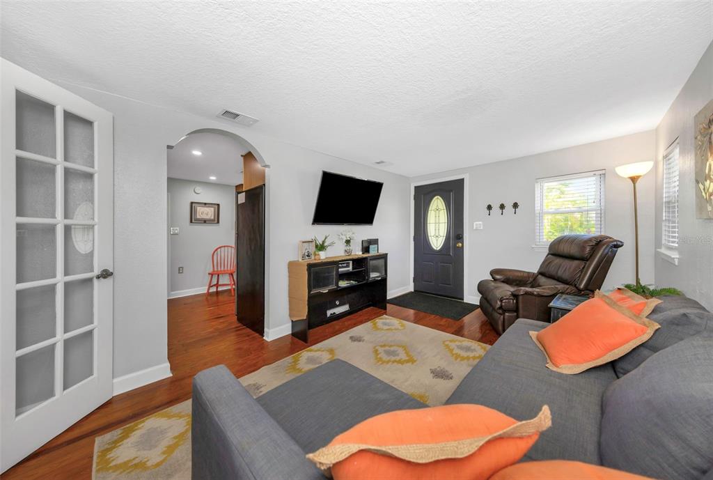 A living room features a gray sofa, a brown recliner, a television, and hardwood floors — 414 TAMPA ROAD, PALM HARBOR, FL
