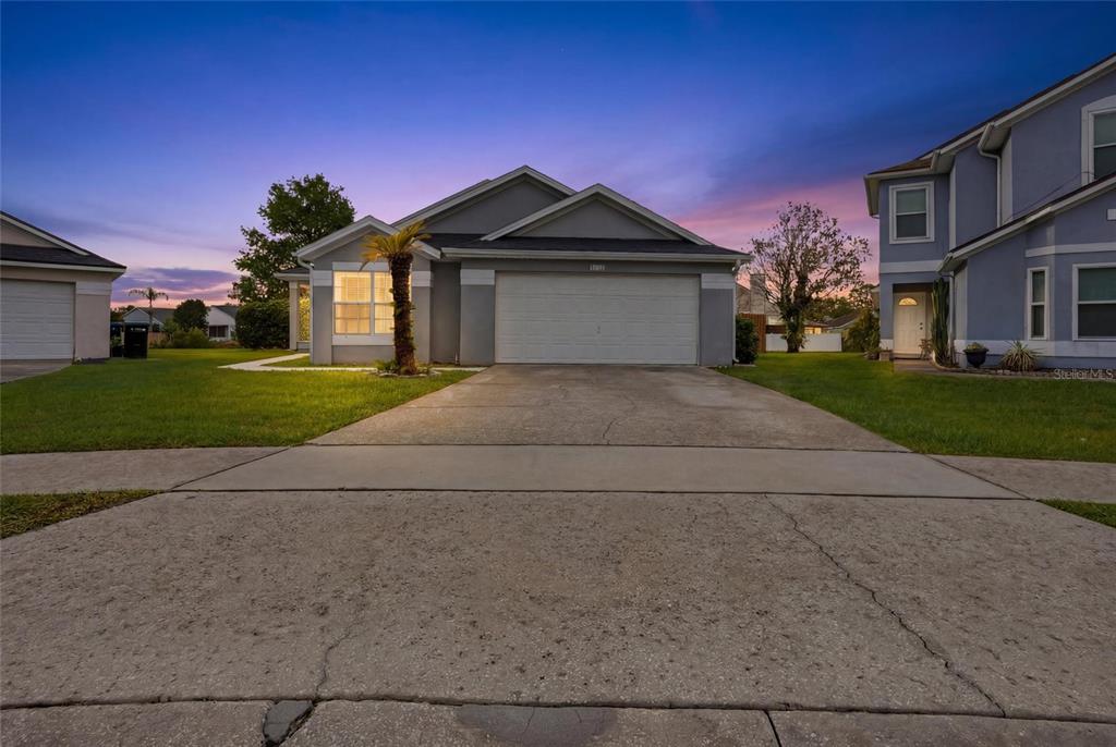 A single-story gray house with a two-car garage and a concrete driveway at dusk — 4702 FORT BRAVO COURT, ORLANDO, FL