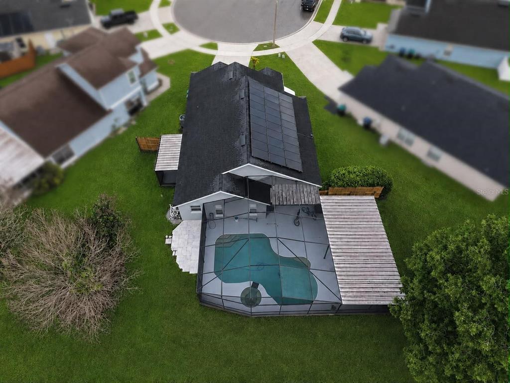 An aerial view of a house with solar panels, a screened-in pool, and a backyard — 4702 FORT BRAVO COURT, ORLANDO, FL