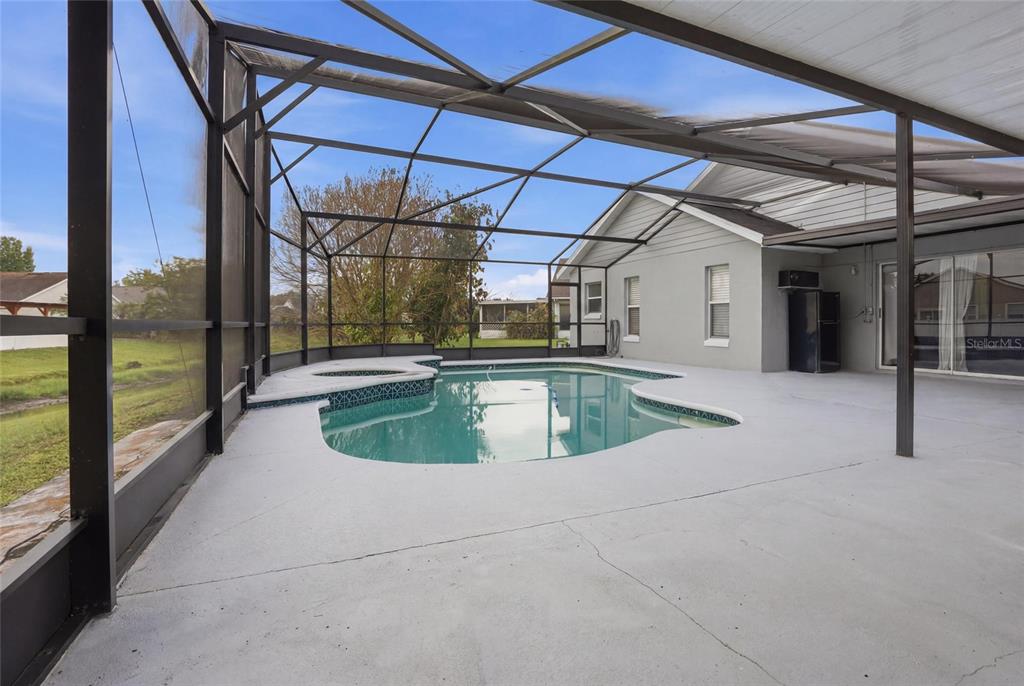 A screened-in patio features a swimming pool with an attached spa and concrete decking — 4702 FORT BRAVO COURT, ORLANDO, FL