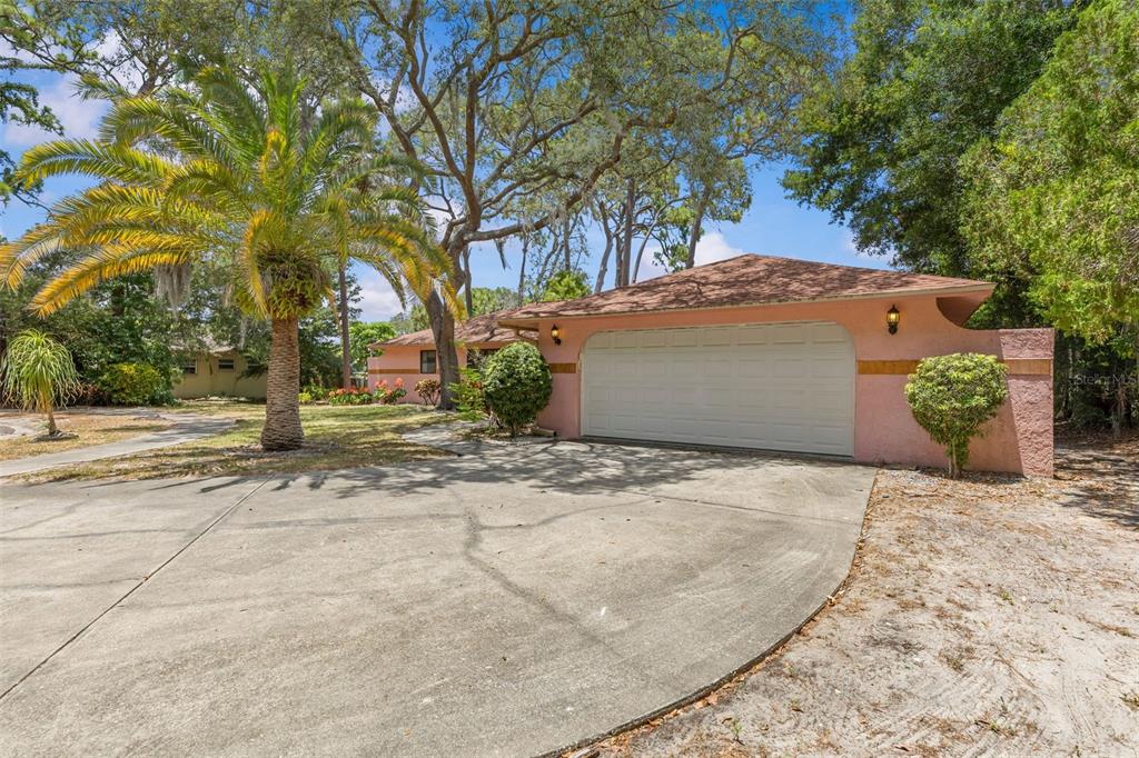 A pink house with a two-car garage and a large palm tree in the front yard — 505 VILLAGE OAK DRIVE, TARPON SPRINGS, FL
