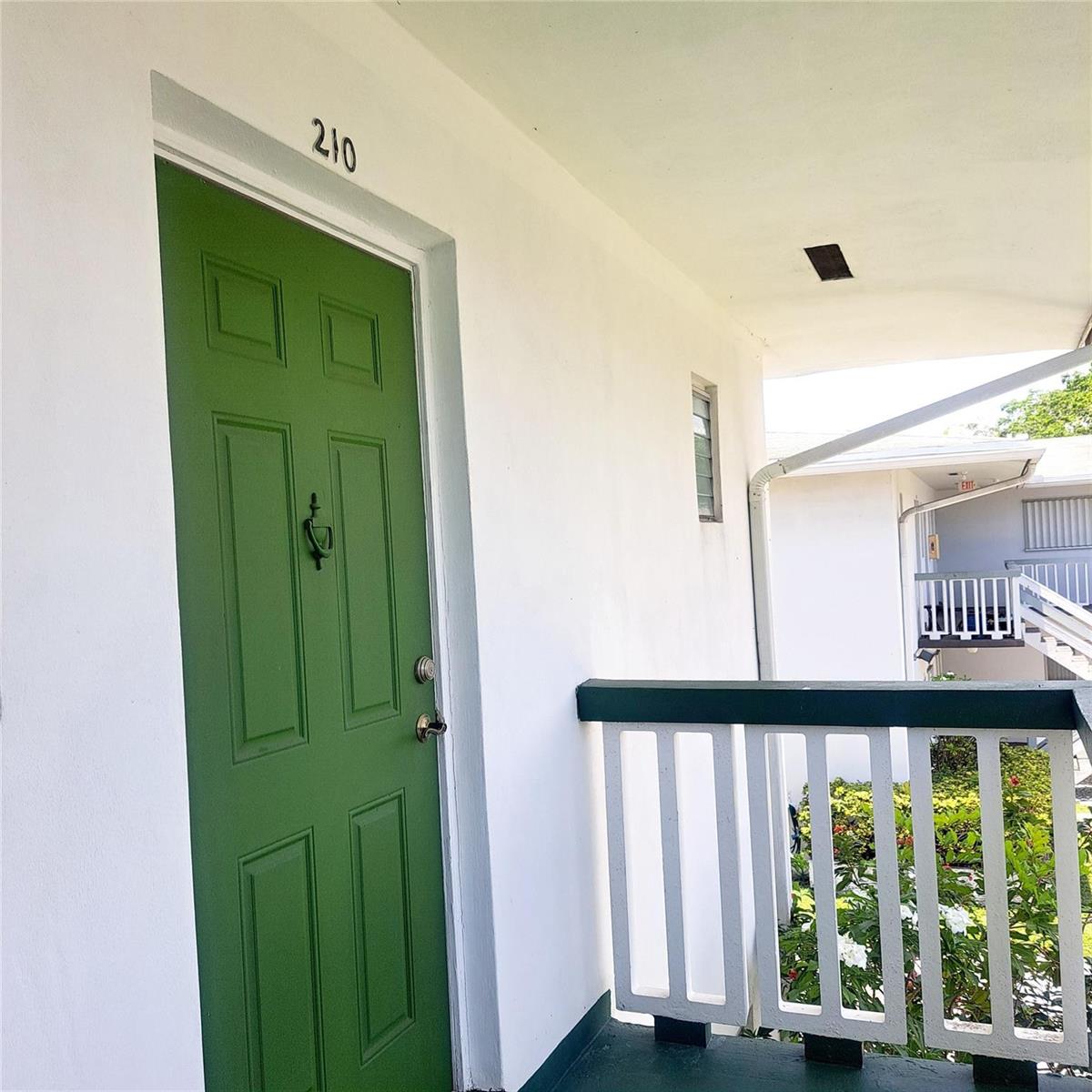 A green front door labeled 210 opens onto an outdoor walkway with a white railing — 6730 Arbor Drive # 210, Miramar FL 33023, MIRAMAR, FL
