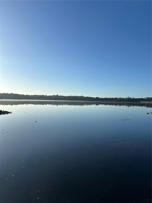 A calm lake reflects the clear blue sky under a line of distant trees — 212 ASHLEY STREET, HAWTHORNE, FL