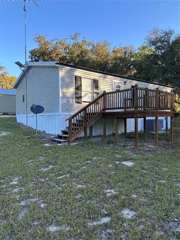 A single-story manufactured home features light-colored siding, a wooden deck, and a metal roof — 212 ASHLEY STREET, HAWTHORNE, FL