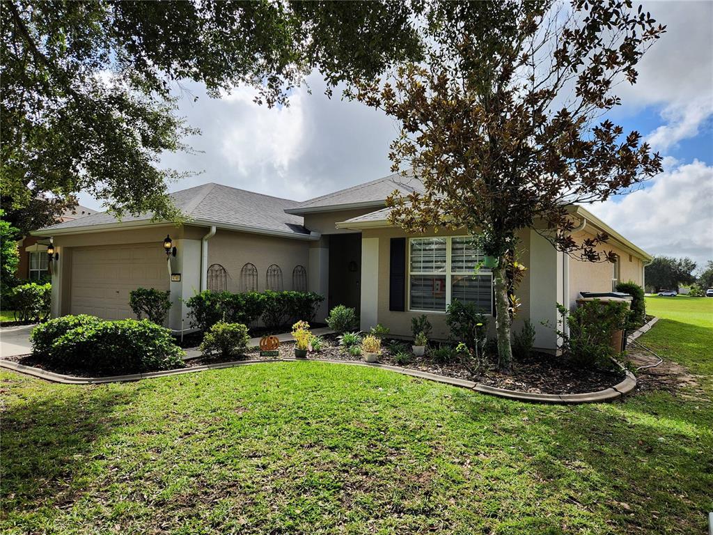 A single-story suburban house with a tan stucco exterior, a two-car garage, and landscaped yard — 4740 SW 41ST STREET, OCALA, FL