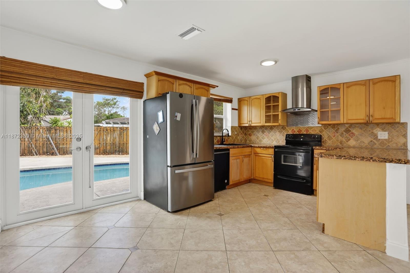 A kitchen with wooden cabinets, stainless steel appliances, and a sliding door to a pool — 2681 NW 63rd Ave, Margate FL 33063, MARGATE, FL