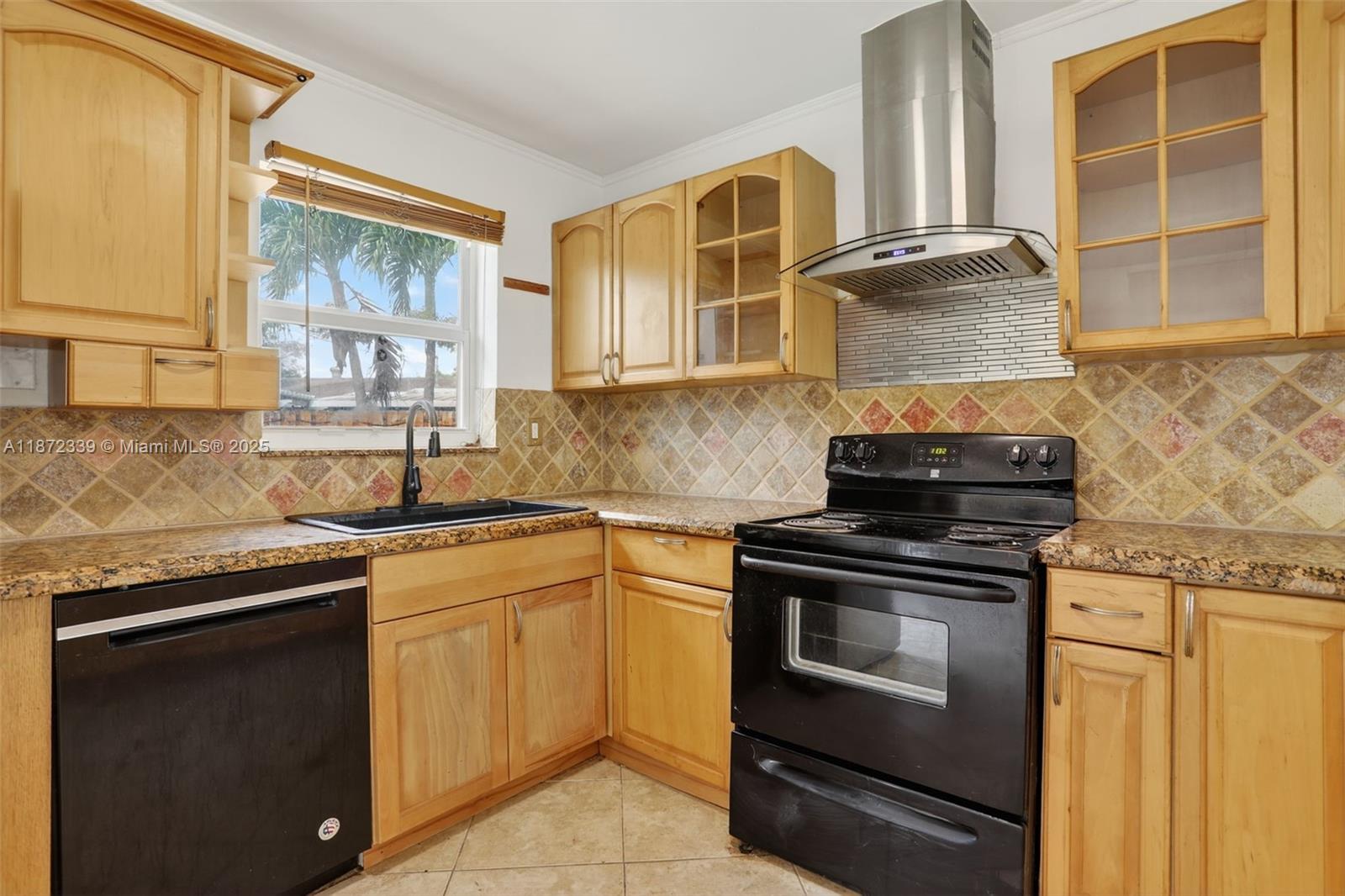 A kitchen features light wood cabinets, granite countertops, black appliances, and a tiled backsplash — 2681 NW 63rd Ave, Margate FL 33063, MARGATE, FL
