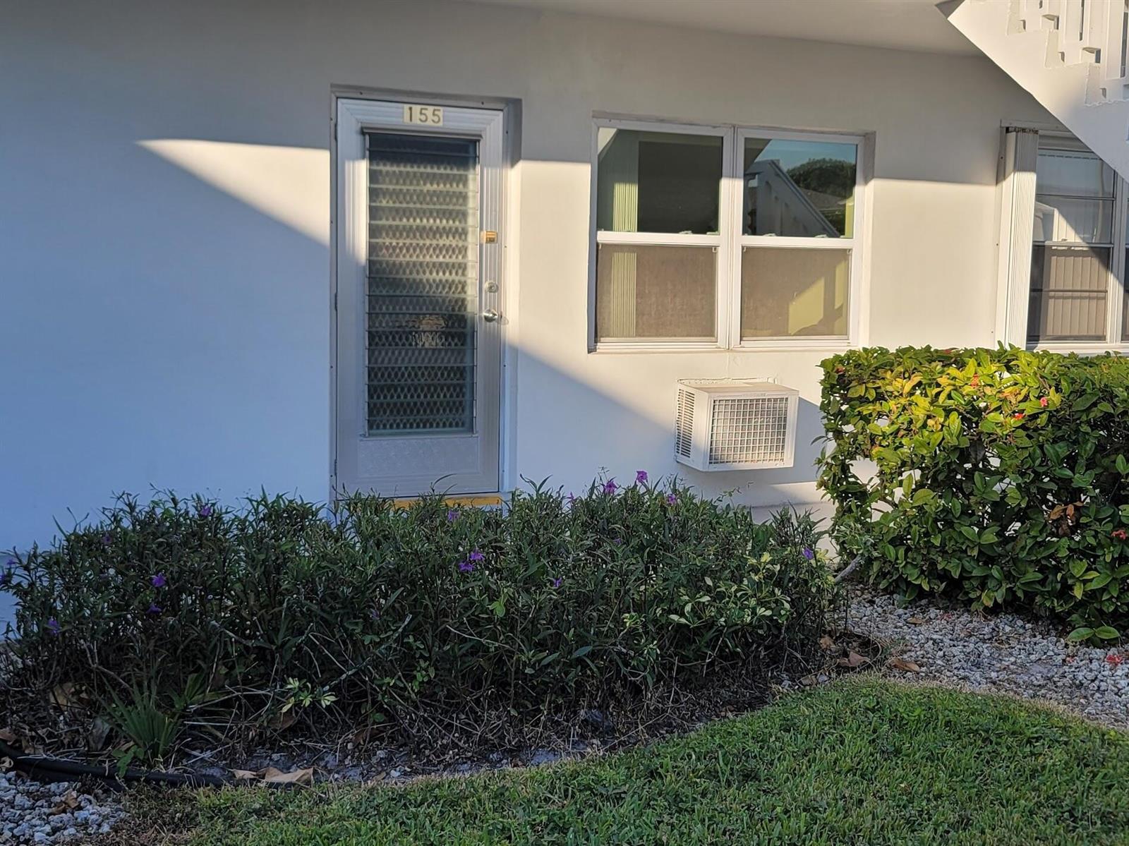 A white exterior wall features a door numbered 155, a window, and a window air conditioner — 155 Coventry, West Palm Beach FL 33417, WEST PALM BEACH, FL
