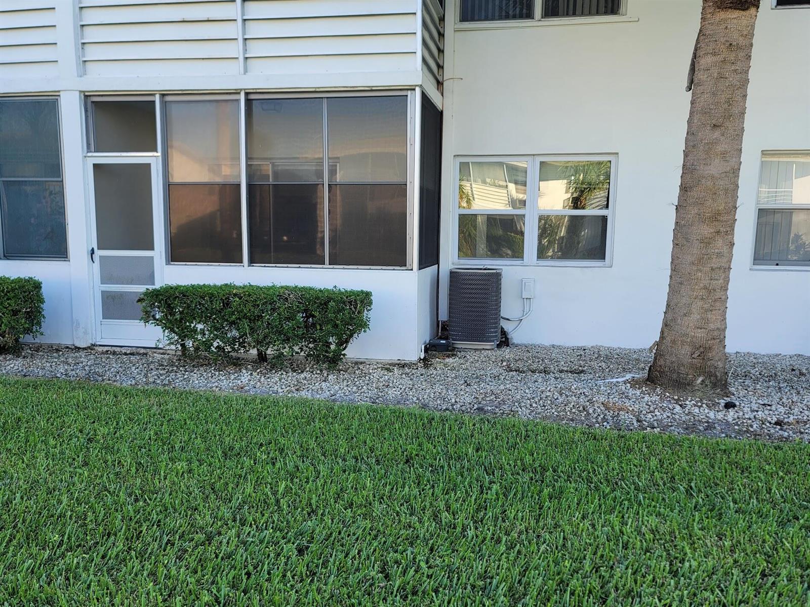 The exterior of a white building features a screened-in porch, an air conditioning unit, and landscaping — 155 Coventry, West Palm Beach FL 33417, WEST PALM BEACH, FL