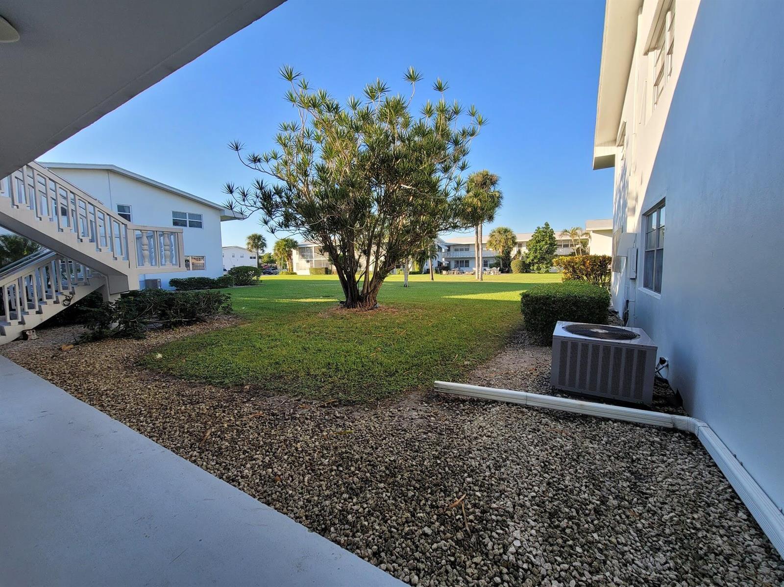 A view from a covered patio looking out at a grassy courtyard with a large tree — 155 Coventry, West Palm Beach FL 33417, WEST PALM BEACH, FL