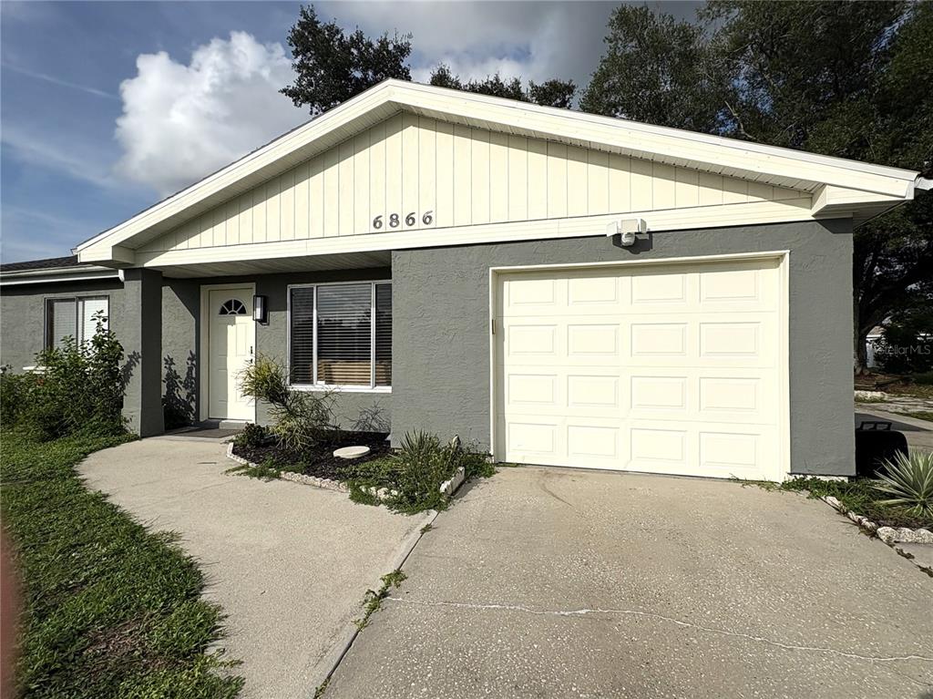 A single-story house with a gray stucco exterior, white trim, and an attached one-car garage — 6866 KAPPA PLACE, NORTH PORT, FL