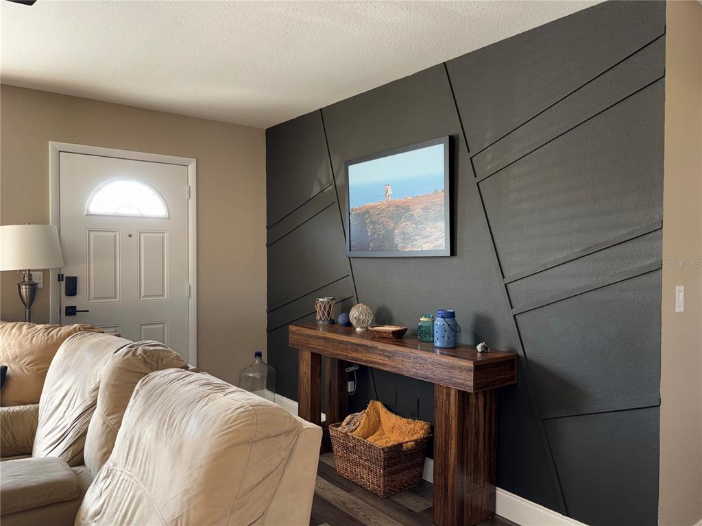 A living room features a dark accent wall with geometric trim and a wooden console table — 6866 KAPPA PLACE, NORTH PORT, FL