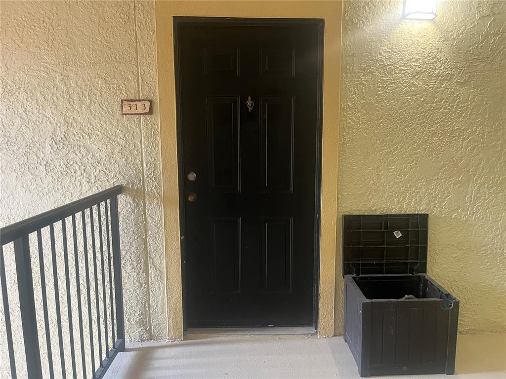 A black apartment door labeled 313 sits next to a small outdoor storage bin — 1325 ROTONDA POINT UNIT 313, LAKE MARY, FL