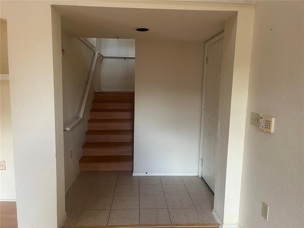 An entryway features a tiled floor, a white door, and wooden stairs leading upward — 1325 ROTONDA POINT UNIT 313, LAKE MARY, FL