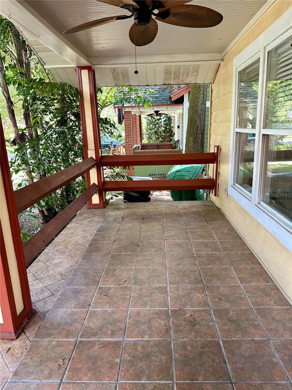 A covered porch features tiled flooring, a ceiling fan, and a wooden railing — 1209 E COMANCHE AVENUE, TAMPA, FL