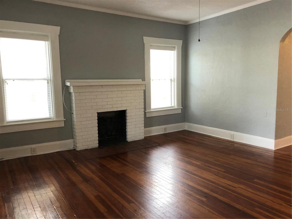A living room with hardwood floors, a white brick fireplace, and light blue walls — 1209 E COMANCHE AVENUE, TAMPA, FL