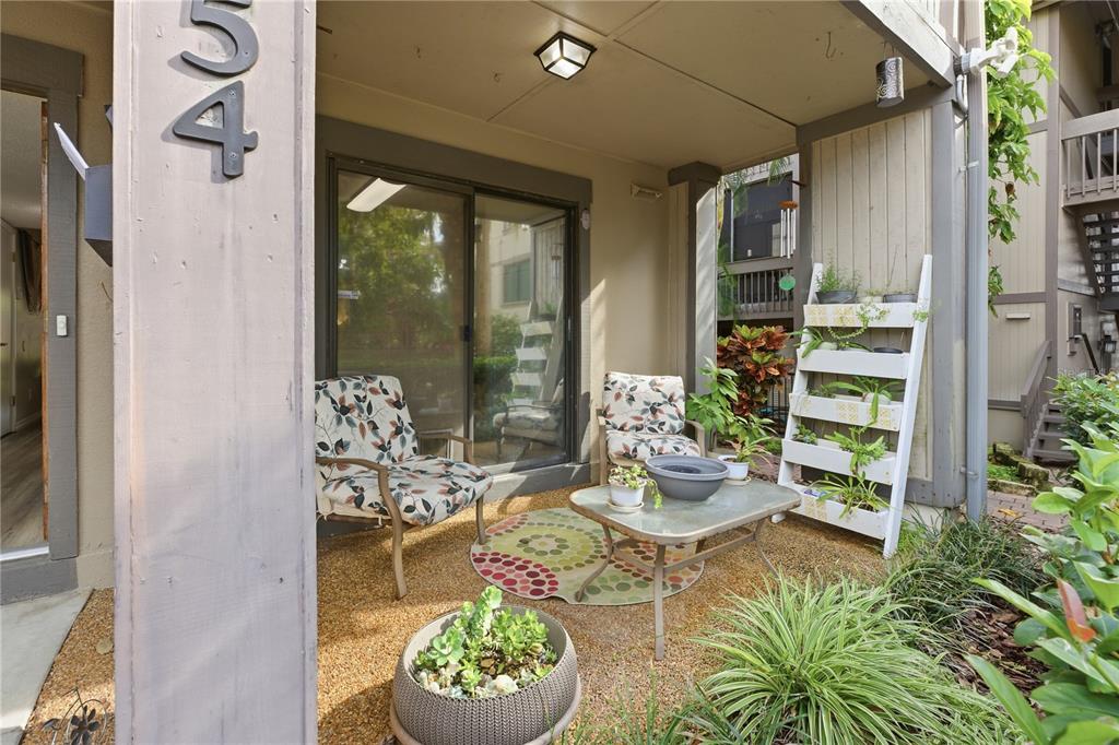 A covered patio features two patterned chairs, a glass-top table, and a white tiered planter — 654 LAKE VILLAS DRIVE UNIT 654, ALTAMONTE SPRINGS, FL
