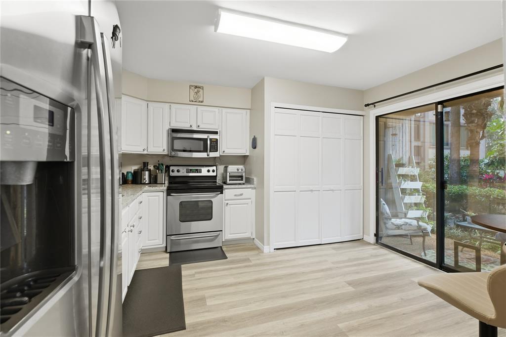 A kitchen with white cabinets, stainless steel appliances, and a sliding glass door to a patio — 654 LAKE VILLAS DRIVE UNIT 654, ALTAMONTE SPRINGS, FL