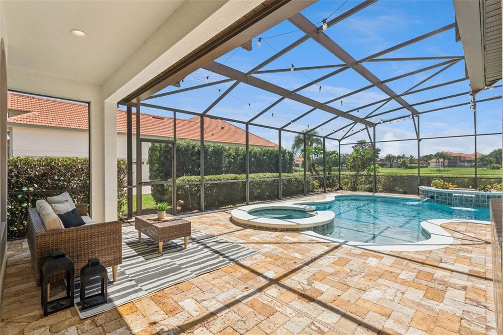 A screened-in patio features a pool, a hot tub, and a wicker seating area — 5746 OXFORD MOOR BOULEVARD, WINDERMERE, FL