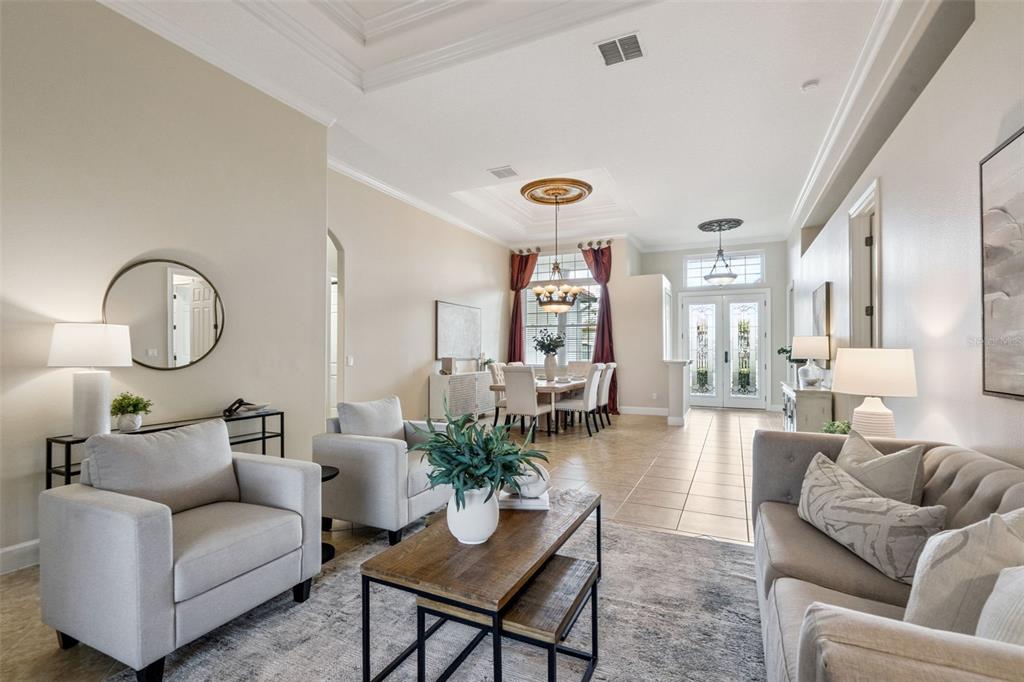 A living room and dining area feature neutral furniture, tile flooring, and high tray ceilings — 5746 OXFORD MOOR BOULEVARD, WINDERMERE, FL