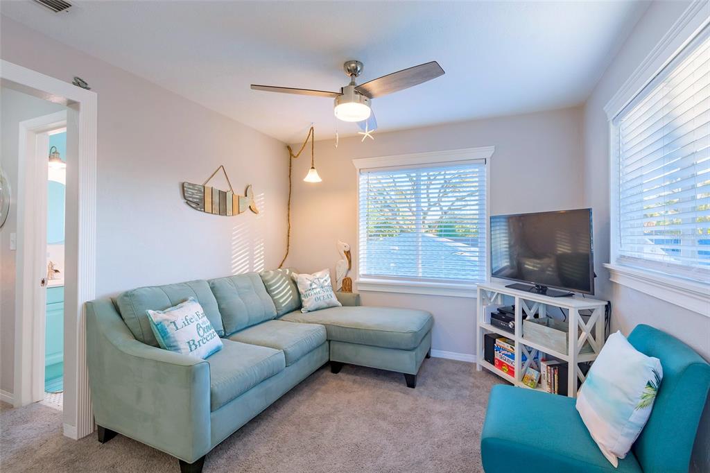 A living room features a light blue sectional sofa, a television, and a ceiling fan — 2035 28TH AVENUE N UNIT 1/2, ST PETERSBURG, FL