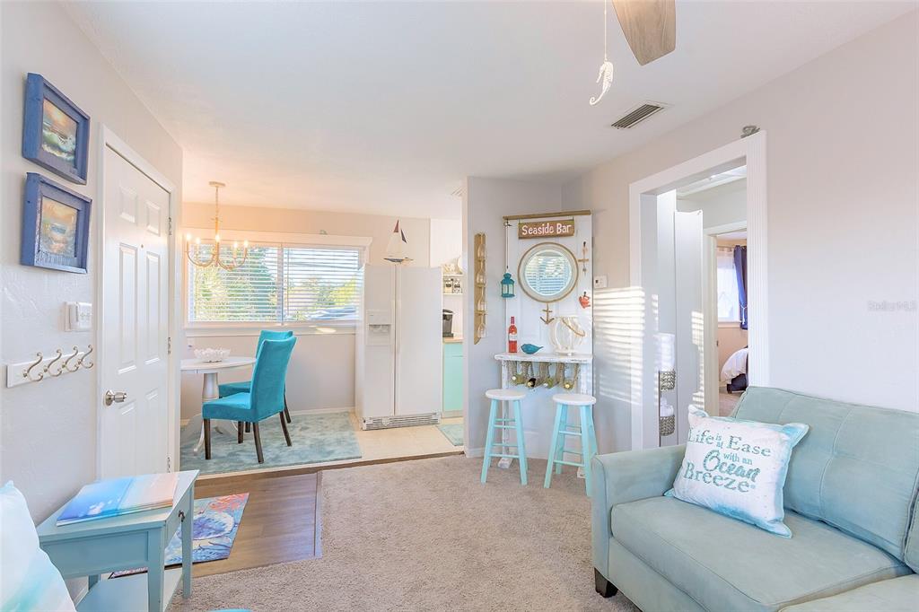 A living room and dining area feature light-colored walls, carpet, and coastal-themed decor — 2035 28TH AVENUE N UNIT 1/2, ST PETERSBURG, FL