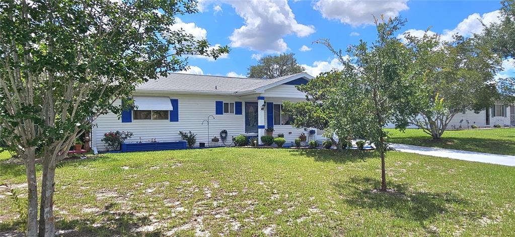 A white single-story house with blue shutters and a front porch sits on a lawn — 10957 SW 79TH TERRACE, OCALA, FL