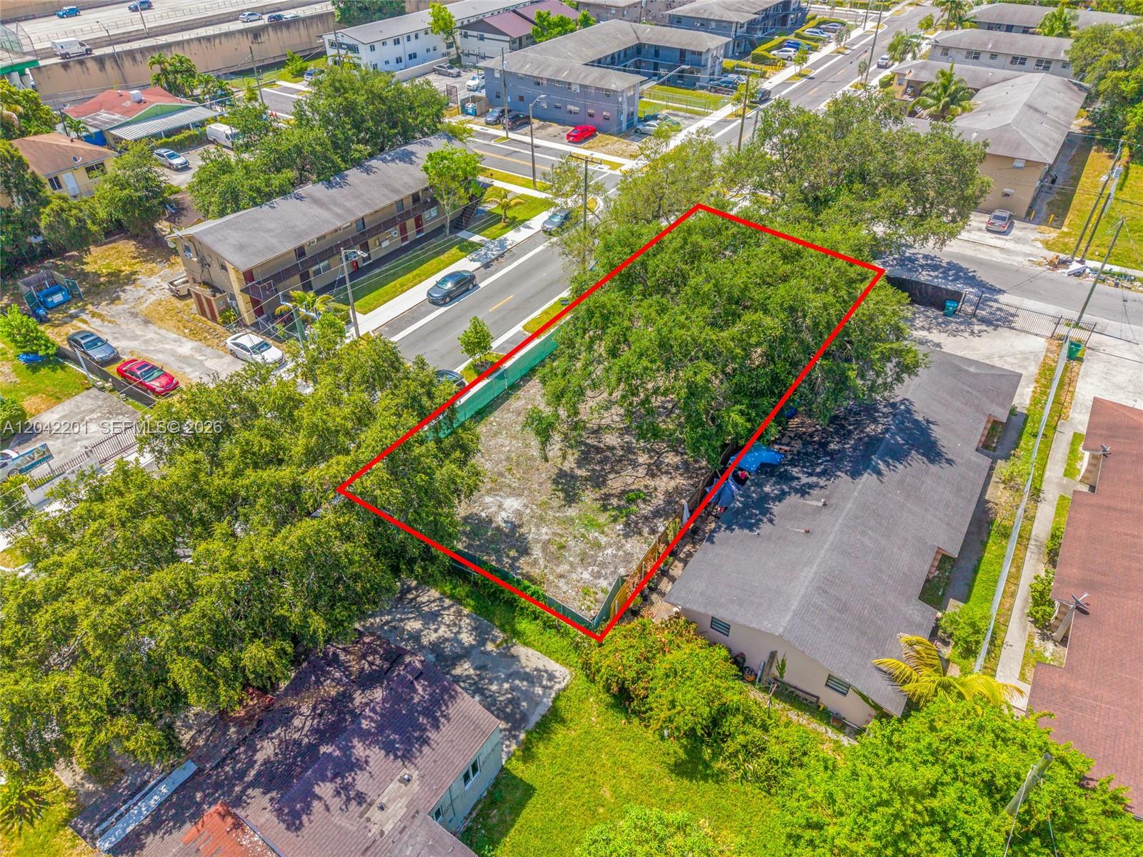 An aerial view shows a vacant, tree-covered rectangular lot outlined in red between residential buildings — 605 NW 65th St, Miami FL 33150, MIAMI, FL