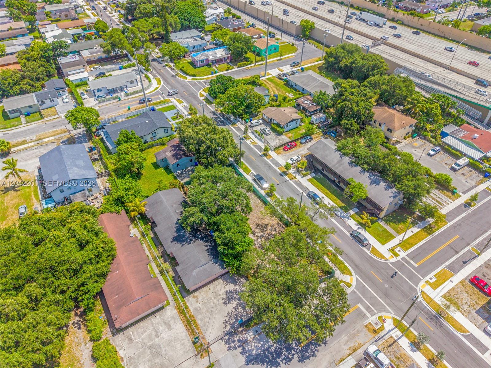 An aerial view shows a residential neighborhood with houses, apartment buildings, and a nearby highway — 605 NW 65th St, Miami FL 33150, MIAMI, FL