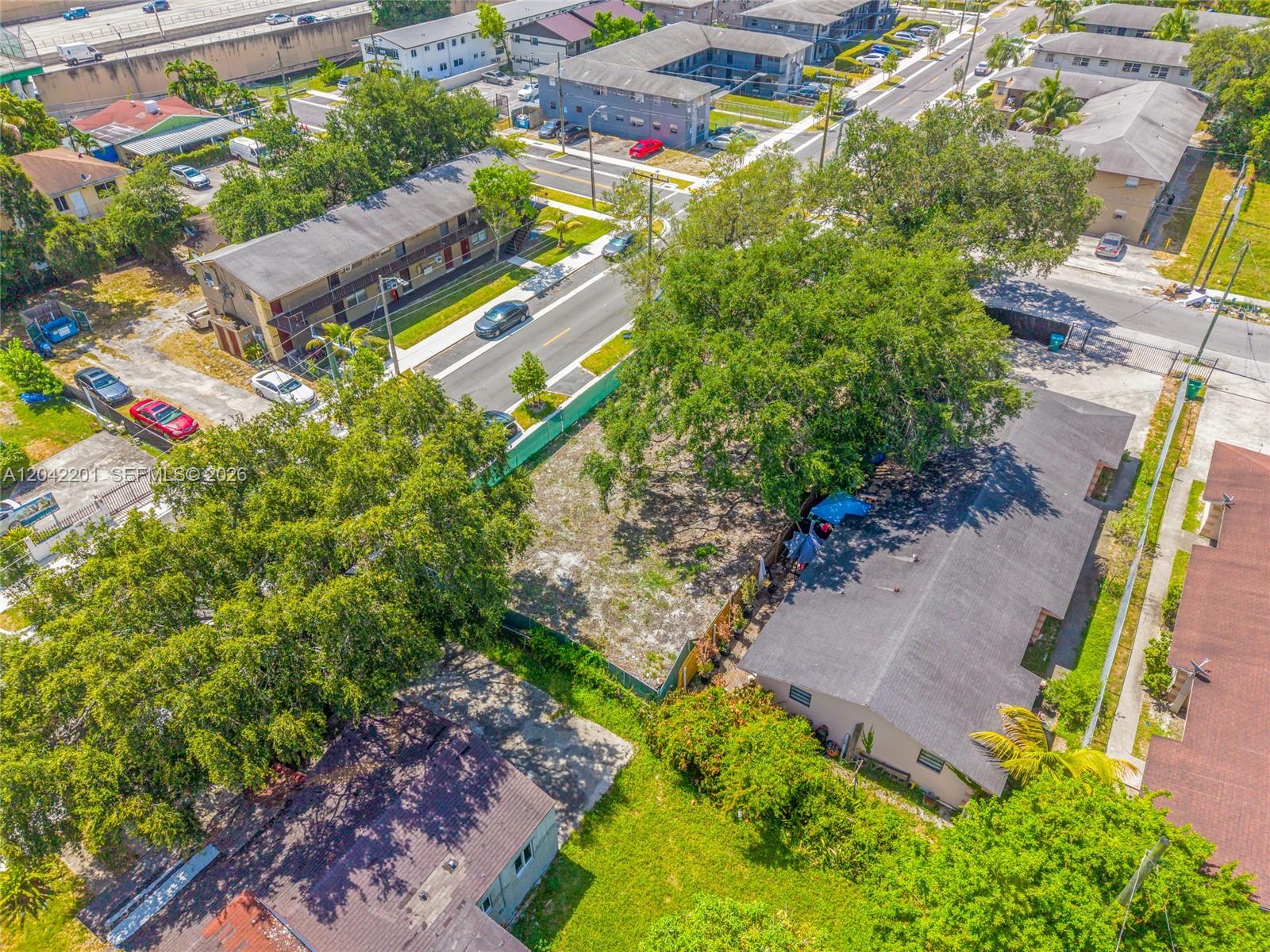 An aerial view shows a vacant lot situated between residential buildings and a street — 605 NW 65th St, Miami FL 33150, MIAMI, FL