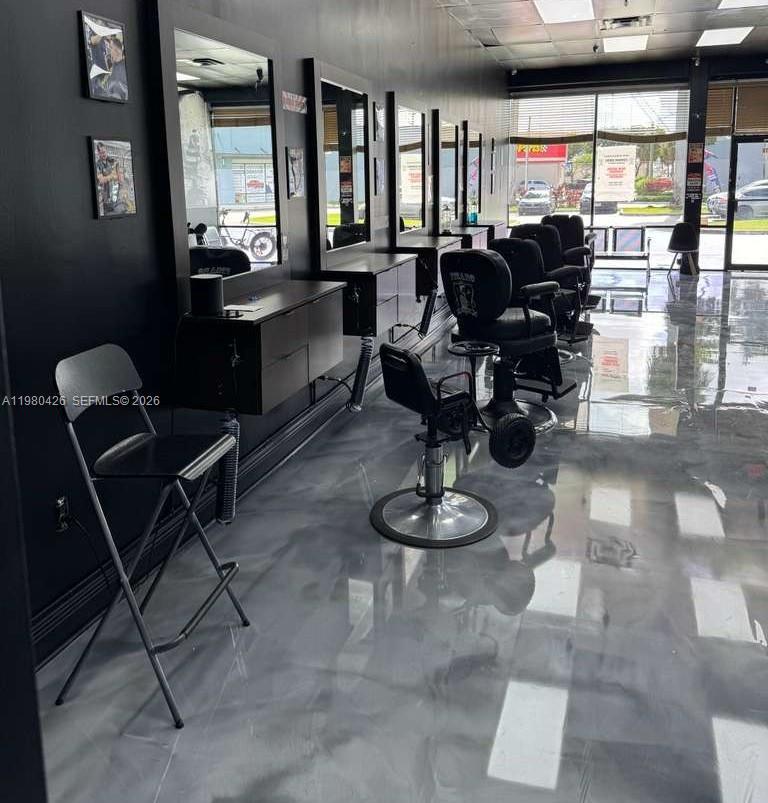 A modern barbershop interior features black styling stations, leather chairs, and a glossy gray floor — Listing – Barbería Hialeah, Hialeah FL 33012, HIALEAH, FL