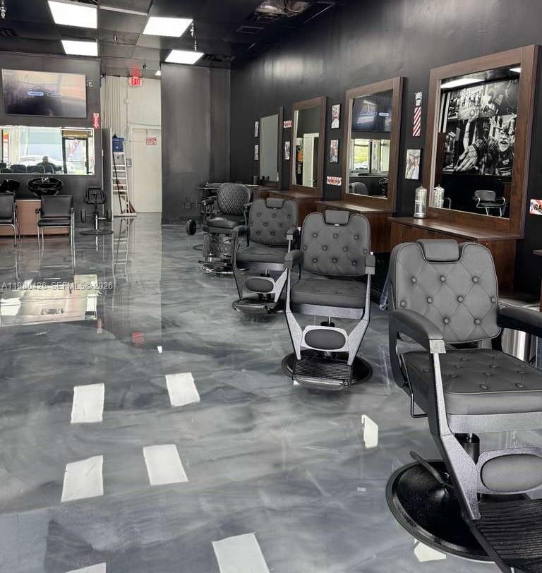 A modern barbershop interior features multiple black styling chairs on a glossy gray epoxy floor — Listing – Barbería Hialeah, Hialeah FL 33012, HIALEAH, FL