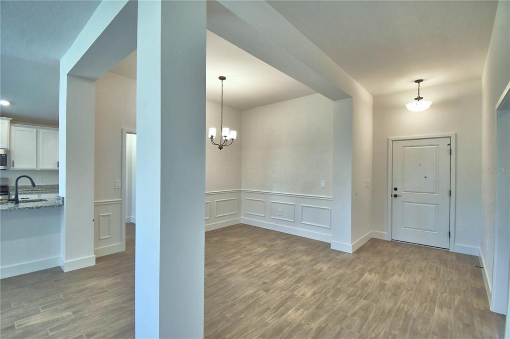 An entryway leads into a dining area featuring wainscoting and wood-look tile flooring — 4964 TENNESSEE LAKE DRIVE, AUBURNDALE, FL