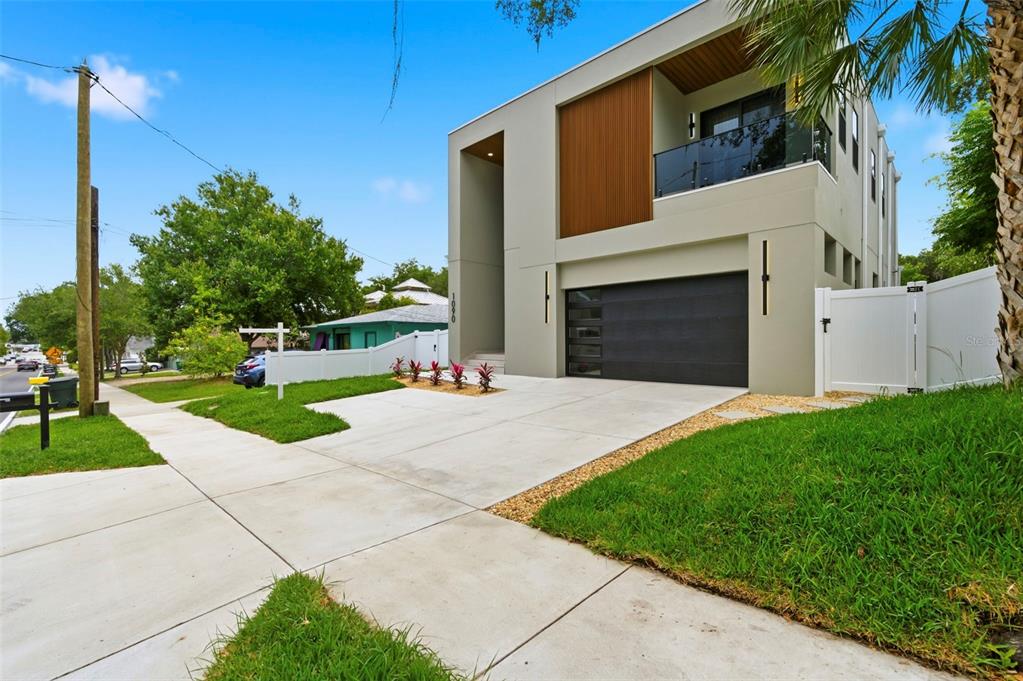 A modern two-story house features a dark garage door, wood paneling, and a balcony — 1090 MAIN STREET, SAFETY HARBOR, FL