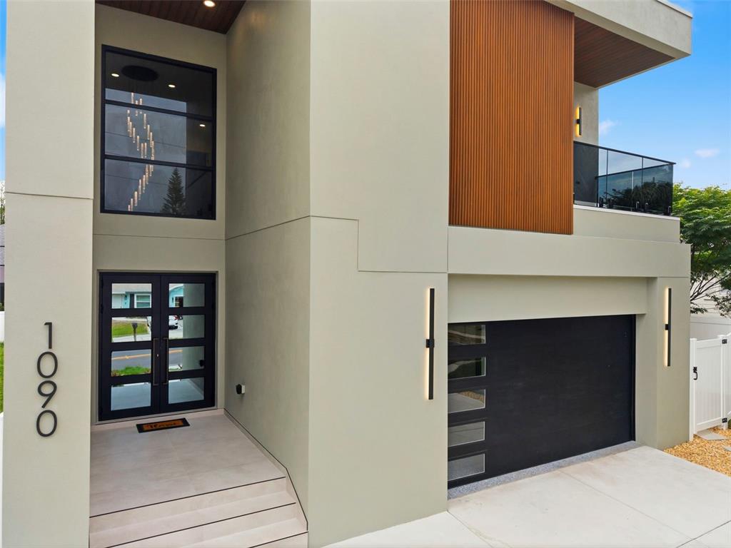 A modern two-story house exterior features a black garage door, front entry, and wood siding — 1090 MAIN STREET, SAFETY HARBOR, FL
