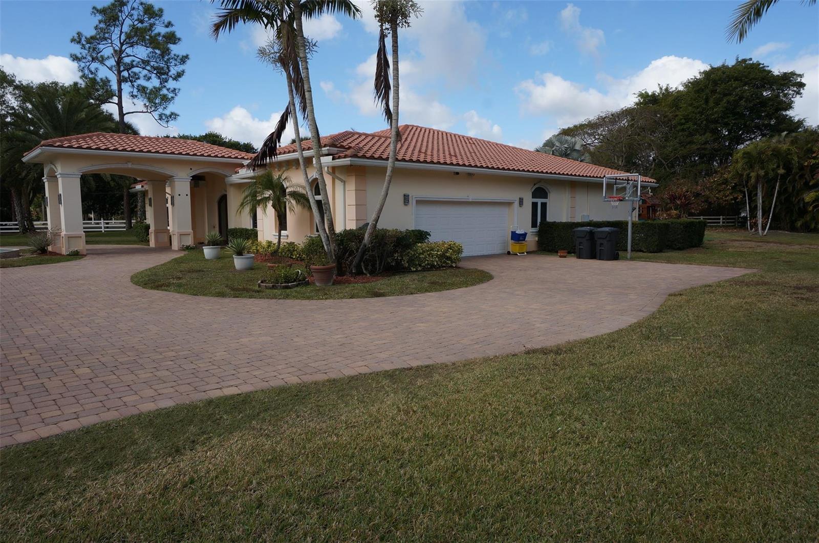 A single-story house with a tile roof, a circular paver driveway, and a porte-cochère — 650 E Rambling Drive, Wellington FL 33414, WELLINGTON, FL