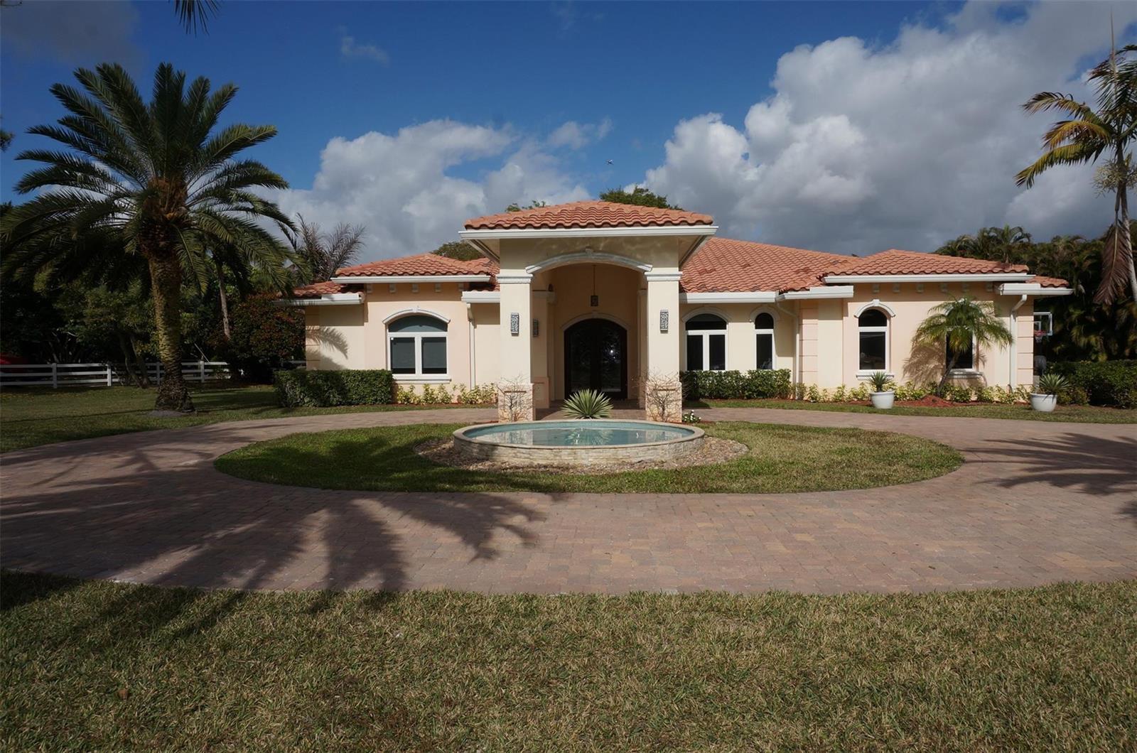 A single-story house with a tile roof and a circular driveway featuring a central fountain — 650 E Rambling Drive, Wellington FL 33414, WELLINGTON, FL