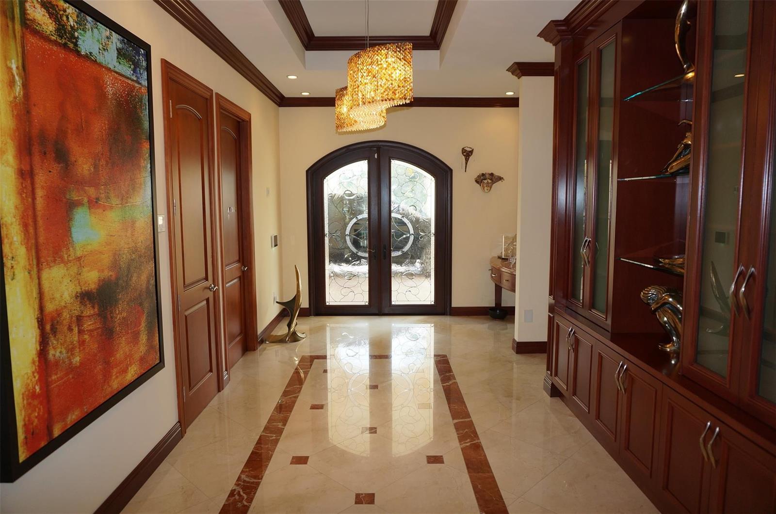 A grand foyer features marble floors, a crystal chandelier, dark wood cabinetry, and double doors — 650 E Rambling Drive, Wellington FL 33414, WELLINGTON, FL