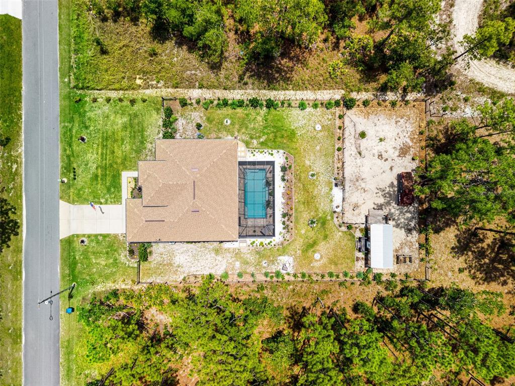 An aerial view shows a house with a screened pool and a large backyard — 11096 WOOD OWL AVENUE, WEEKI WACHEE, FL