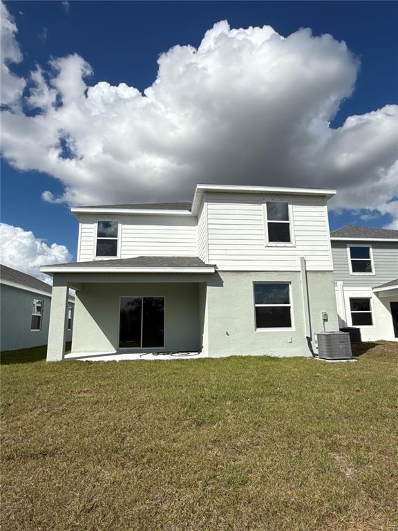 The rear exterior of a two-story house features a covered patio and a grassy yard — 13025 RED DEER PLACE, PARRISH, FL