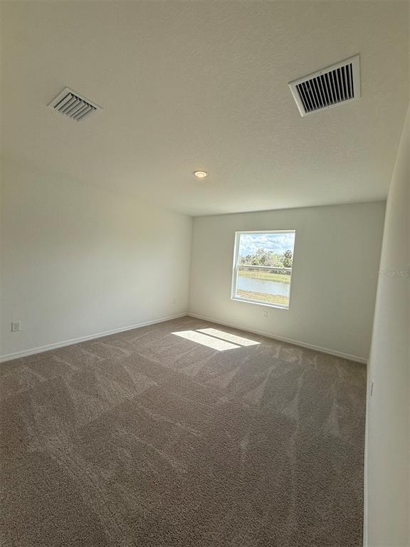 An empty bedroom features beige carpeting, white walls, a single window, and two ceiling vents — 13025 RED DEER PLACE, PARRISH, FL