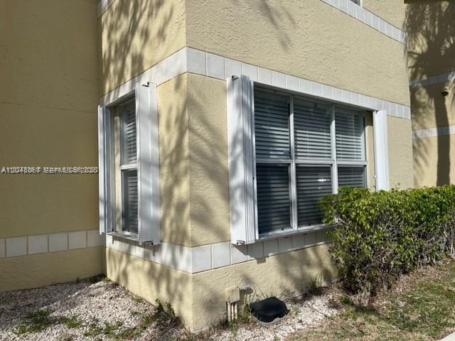 A two-story yellow stucco apartment building with a red tile roof and parking lot — SUNRISE, FL