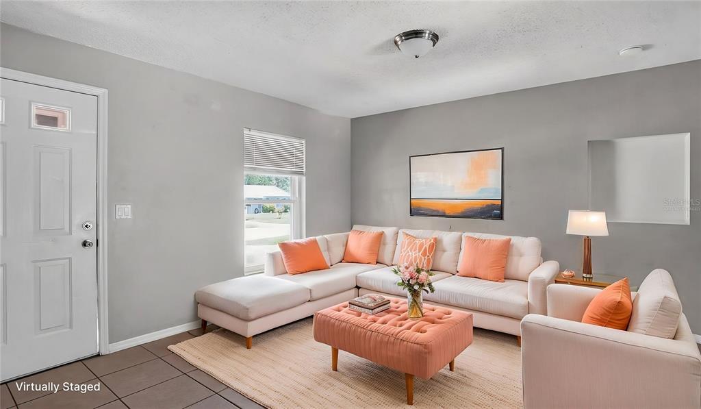 A living room features a sectional sofa, a tufted ottoman, and light gray walls — 1310 NE 20TH STREET, OCALA, FL