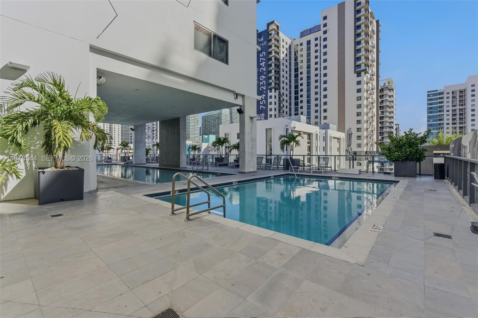 An outdoor swimming pool area with lounge chairs and palm trees on a building terrace — 229 SW 9th St # 407, Miami FL 33130, MIAMI, FL