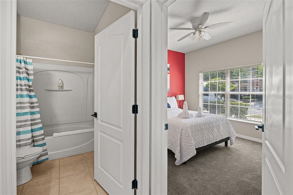 A view through an open doorway shows a bathroom with a tub and a bedroom — 2344 CARAVELLE CIRCLE, KISSIMMEE, FL