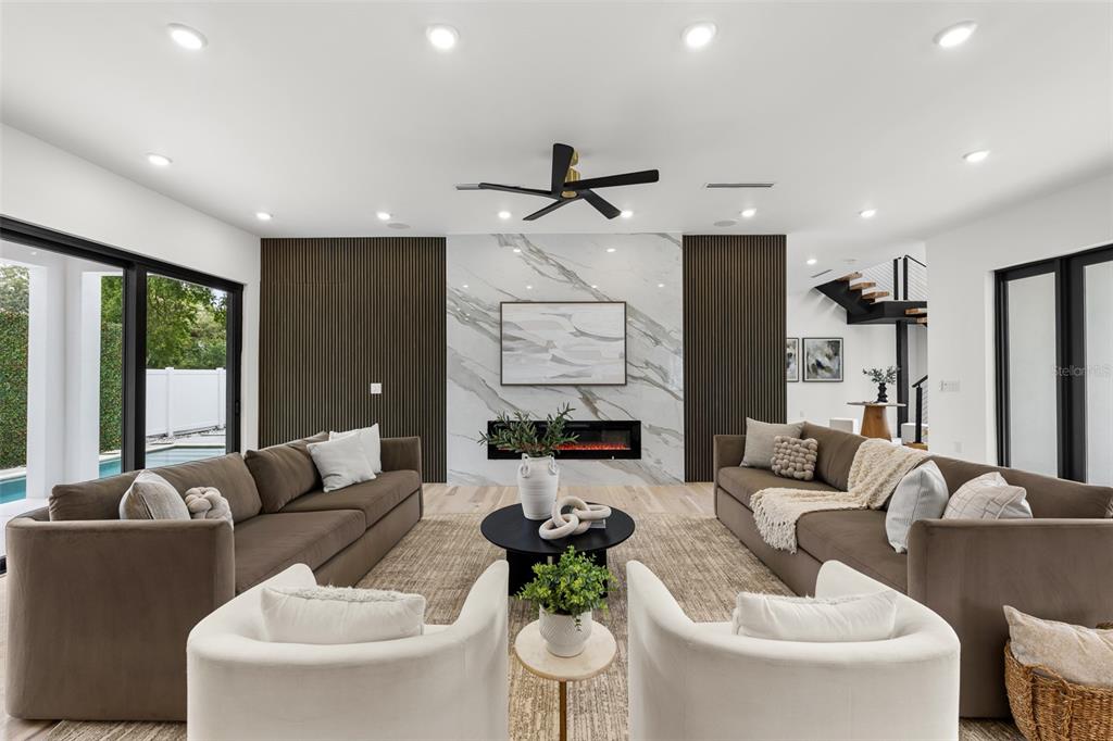A modern kitchen features a large marble island, wood cabinetry, black upper cabinets, and five barstools — 12870 N ARMENIA AVENUE, TAMPA, FL